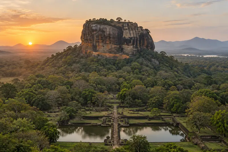 A flat-topped granite rock rises above forest and ancient gardens with stone-edged ponds at sunrise.